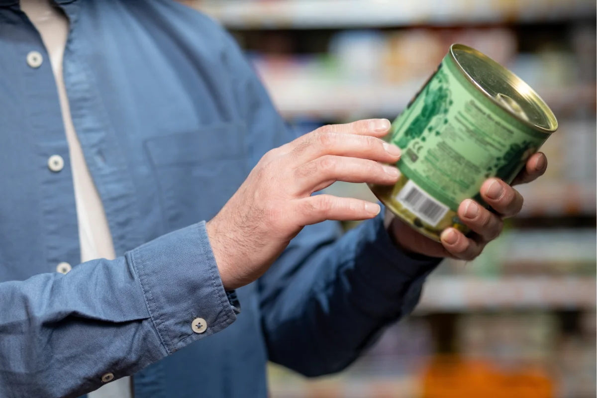 Sujeto agarrando una lata para revisar la fecha de caducidad del alimento