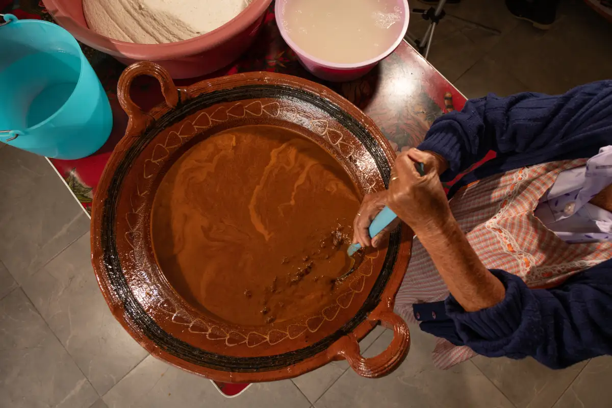 Mujer mayor preparando mole en olla de barro