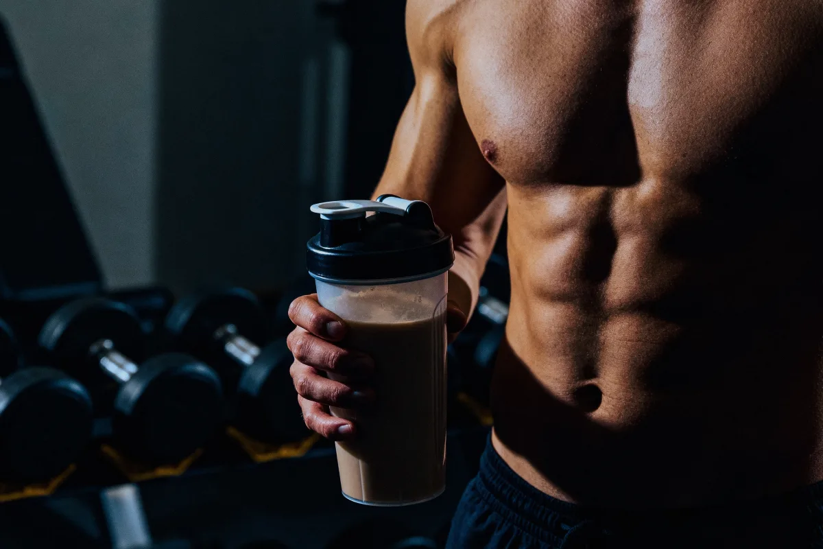 Hombre sin playero sujeta un vaso con un batido de proteina
