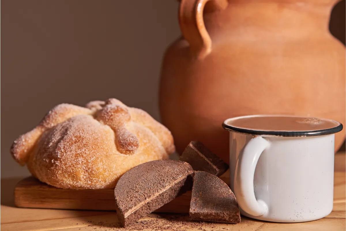 Taza con chocolate caliente y una pieza de pan de muerto