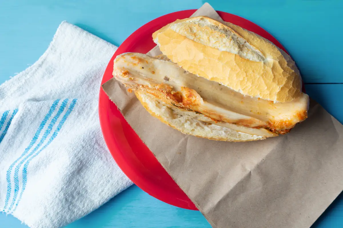 Bolillo partido por la mitad con un tamal en su interior