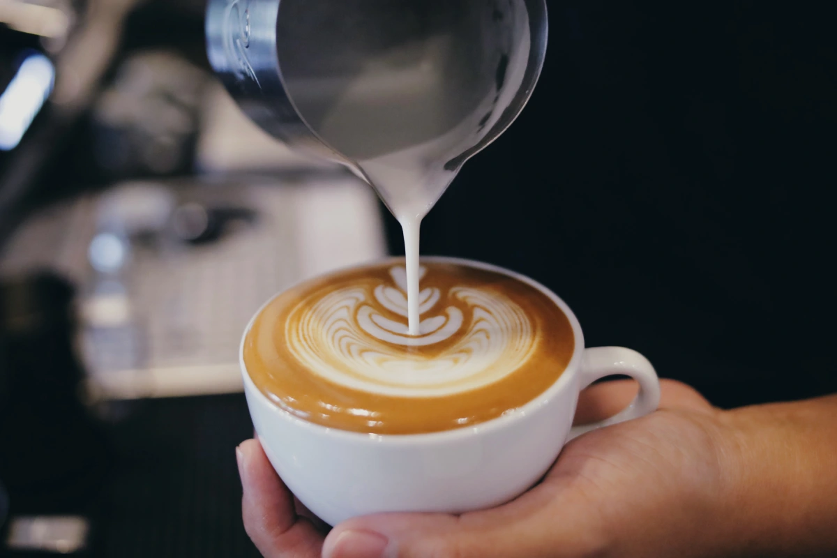 Barista haciendo arte latte sobre una taza
