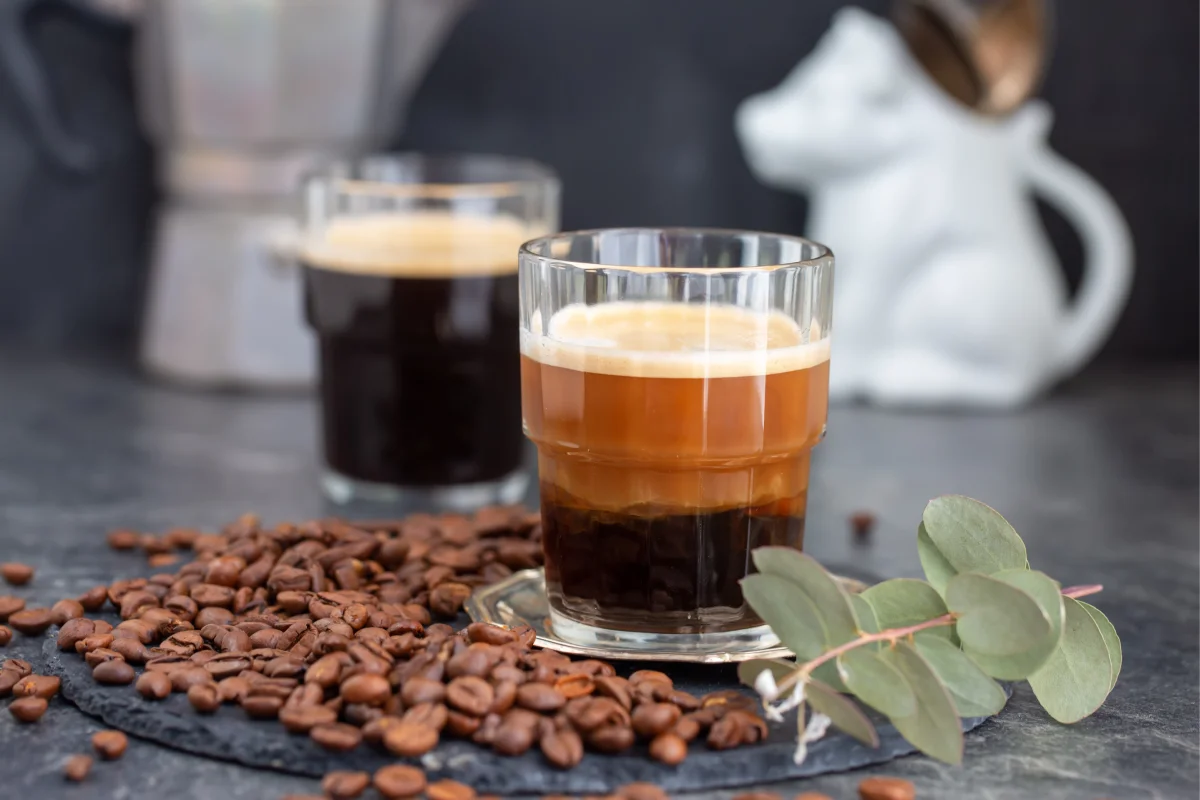 Dos expresos en una mesa con granos de café