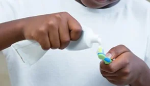 Menino colocando pasta de dente na escova