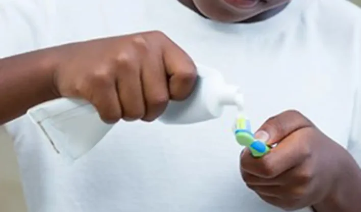 Menino colocando pasta de dente na escova