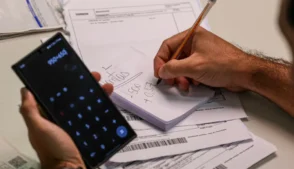 Pessoa branca calcula valor das contas a pagar. IPVA Acre 2026: veja datas de pagamento, descontos e como emitir o boleto