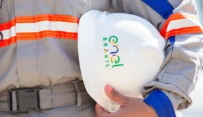 Pessoa segurando capacete com logo da Enel
