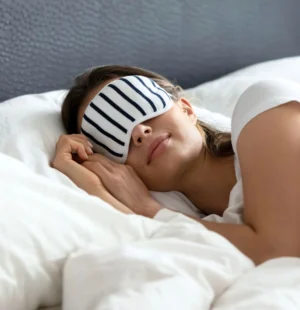 Pessoa dormindo em cama de hotel, com máscara de dormir