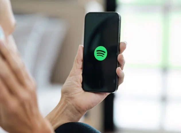 Pessoa segurando celular com logo do Spotify na tela