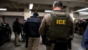 Oficial do ICE de costas, com colete a prova de balas