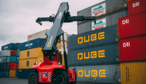 Empilhadeira movimenta contêineres da Qube em pátio logístico.