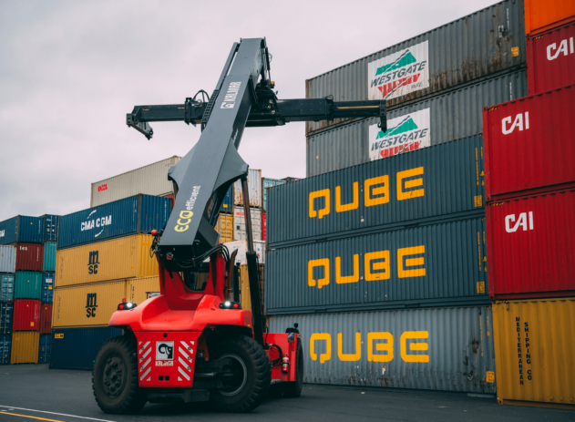 Empilhadeira movimenta contêineres da Qube em pátio logístico.