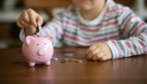 Criança colocando moeda em cofrinho