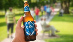 mão segurando garrafa de cerveja zero álcool em um parque