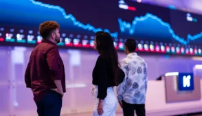 Visitantes observam painel eletrônico com gráficos de desempenho do mercado de ações brasileiro.