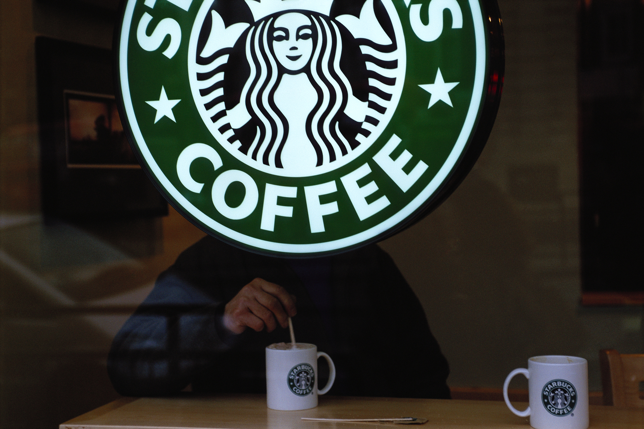 Customer Behind Starbucks Sign in London