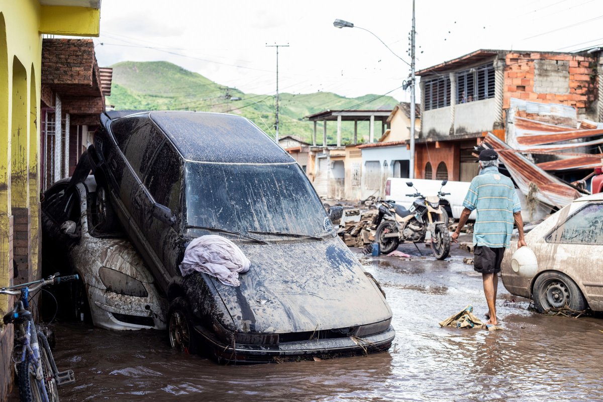 2024 年 7 月 2 日，飓风贝丽尔袭击委内瑞拉库马纳科阿后，洪水过后，一名男子走在受损的车辆附近。