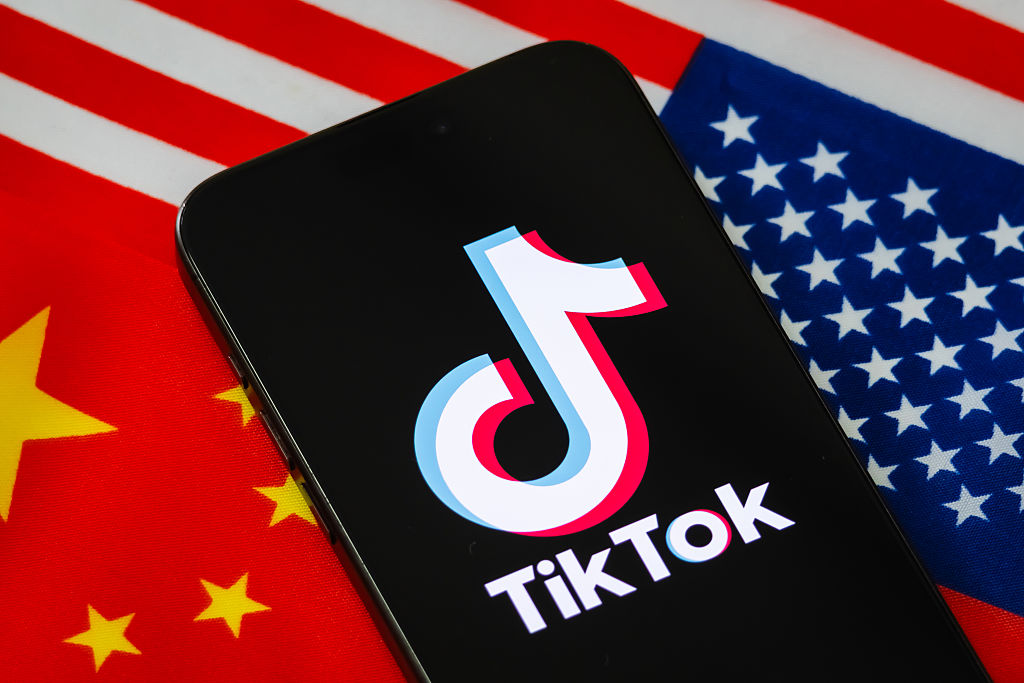 Logo TikTok Dipaparkan Pada Telefon Pintar Berlatar Belakang Bendera China Dan A.S.