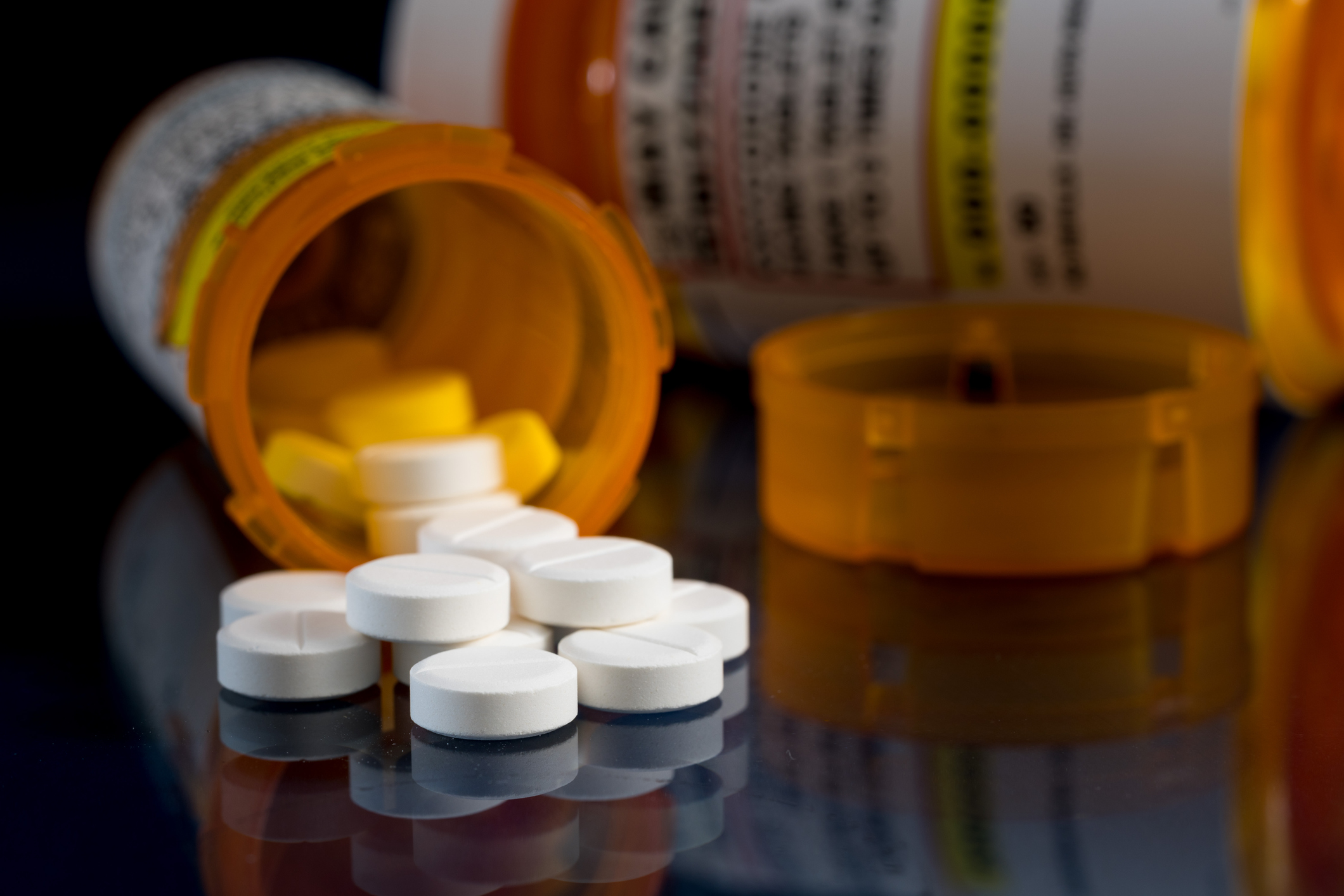 Macro ng mga tableta ng opioid na oxycodone na may mga bote ng reseta laban sa madilim na background
