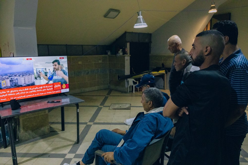 Isang grupo ng mga manggagawa mula Gaza sa Sarriyeh sports club sa okupadong lungsod ng West Bank na Ramallah nanonood ng balita mula sa Al Jazeera mula sa isang ospital sa Gaza, Okt. 12.
