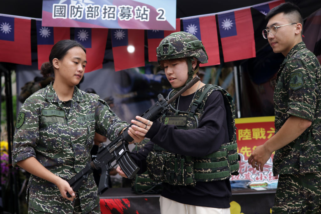 Isang bisita ay sumubok ng military outfit at nakakapit ng baril sa isang Army recruiting booth sa isang pre-National Day street fair, noong Oktubre 09, 2023 sa New Taipei City, Taiwan. 