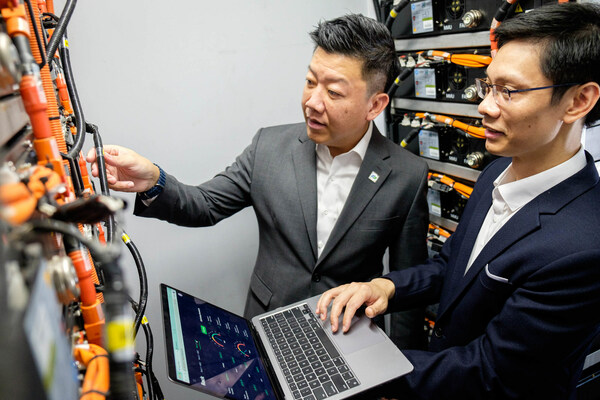 Durapower Group CEO Mr Kelvin Lim (left) and NTU Assistant Professor Hung Dinh Nguyen (right) discussing the AI-powered technology test-bedded in the container-sized energy storage solution, containing Durapower lithium-ion batteries and battery management systems. Asst Prof Hung is holding a laptop showing the cloud-based AI-powered digital twin platform jointly developed by NTU and Durapower to better predict battery performance, enhancing system safety and extending the life of the batteries. Image: NTU Singapore