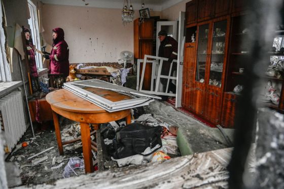 Communal workers fix broken windows in a destroyed house