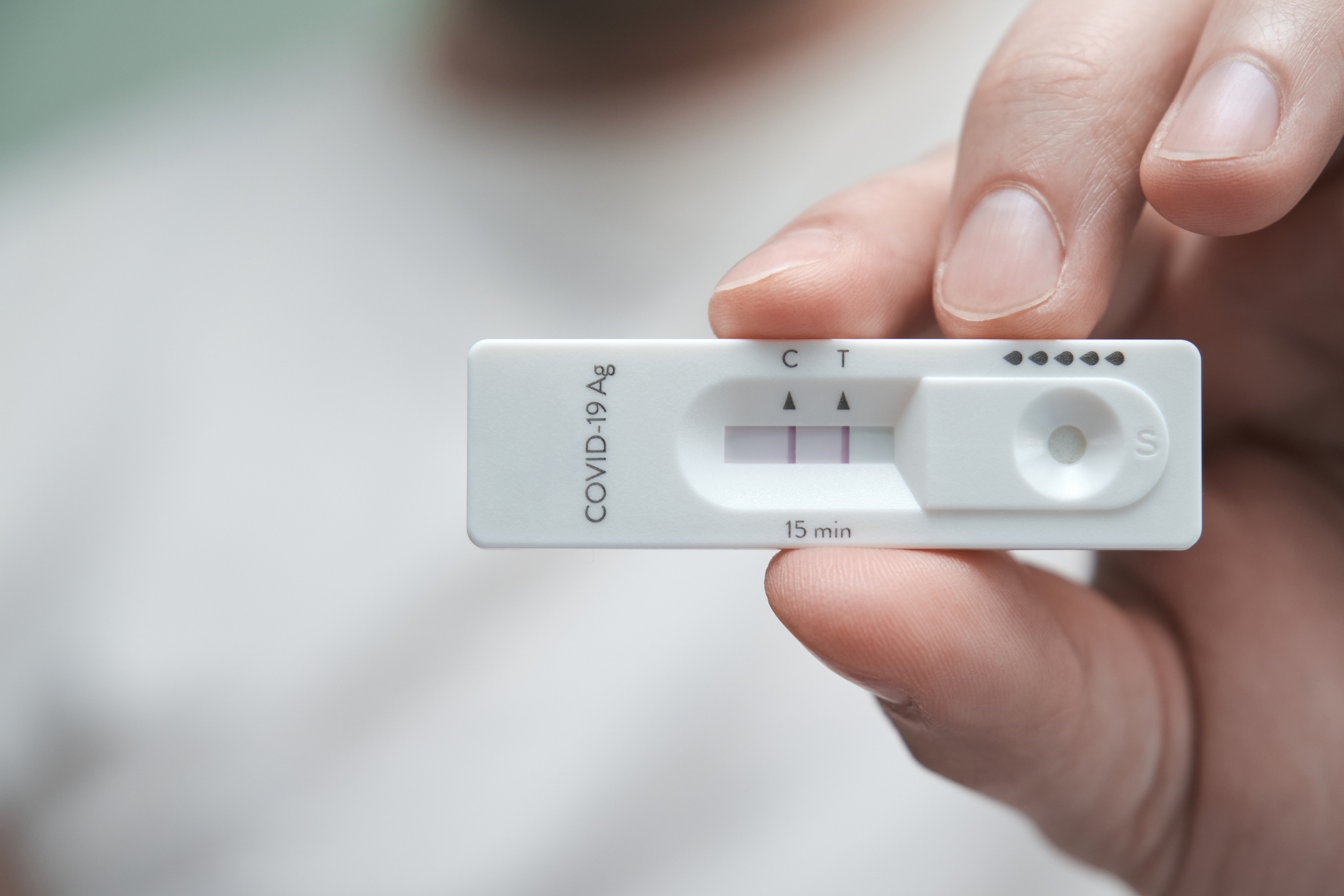 Close-up of a hand holding a positive antigen test for COVID-19.