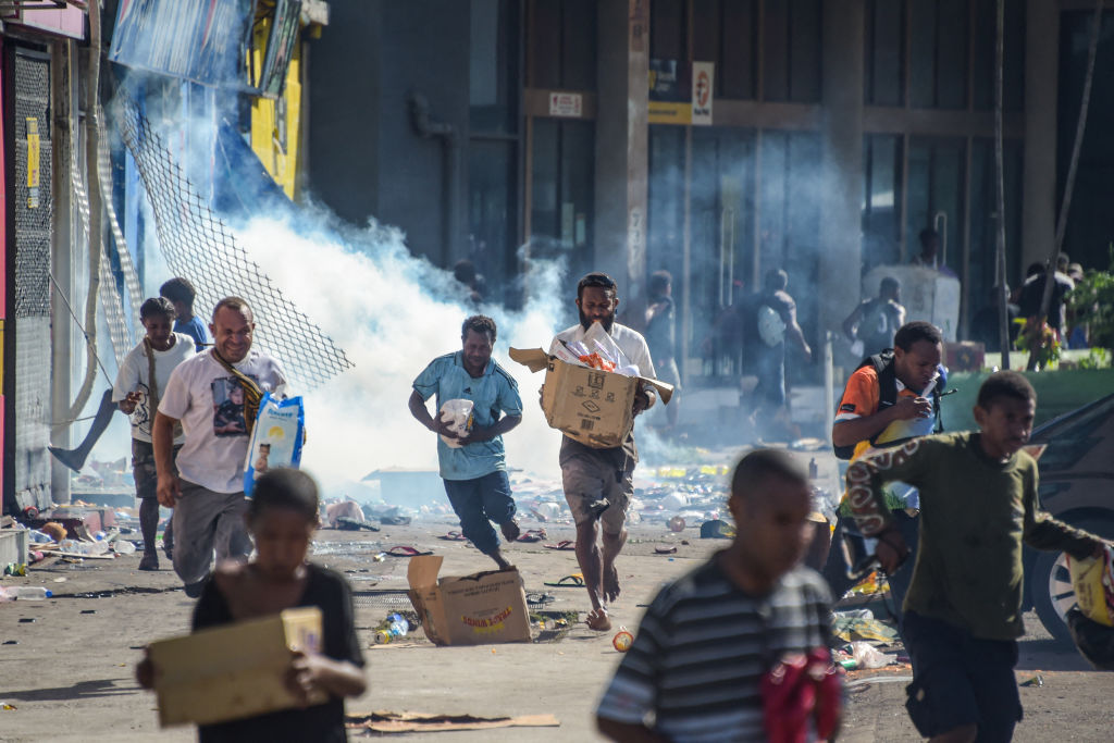 Ang mga tao ay tumatakbo kasama ang mga merchandise habang ang mga crowd ay umalis sa mga tindahan na may ninakaw na mga kalakal sa gitna ng isang estado ng kawalan ng pag-aari sa Port Moresby noong Enero 10, 2024. 