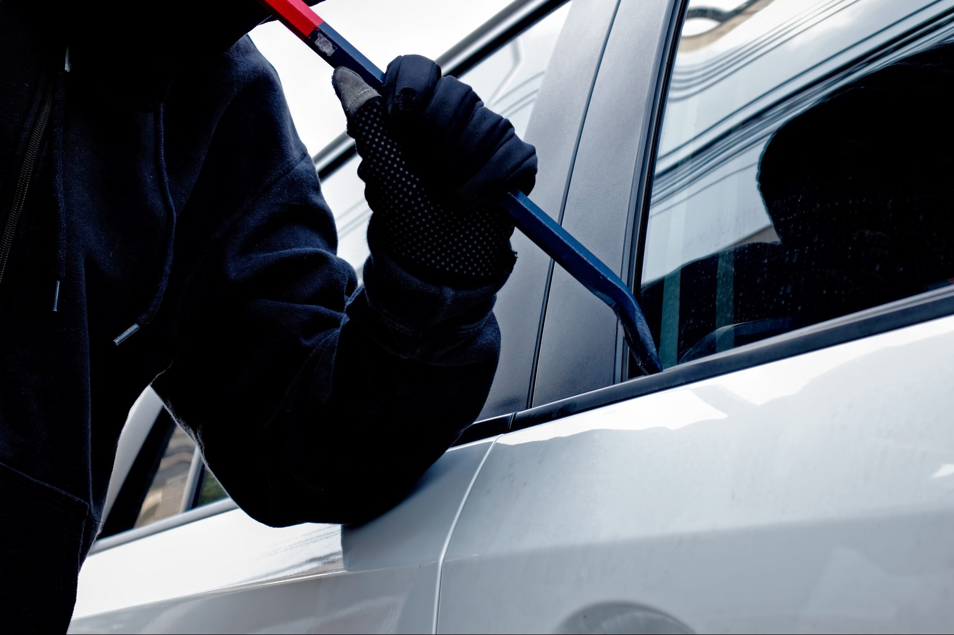 Masked burglar trying to get into a car