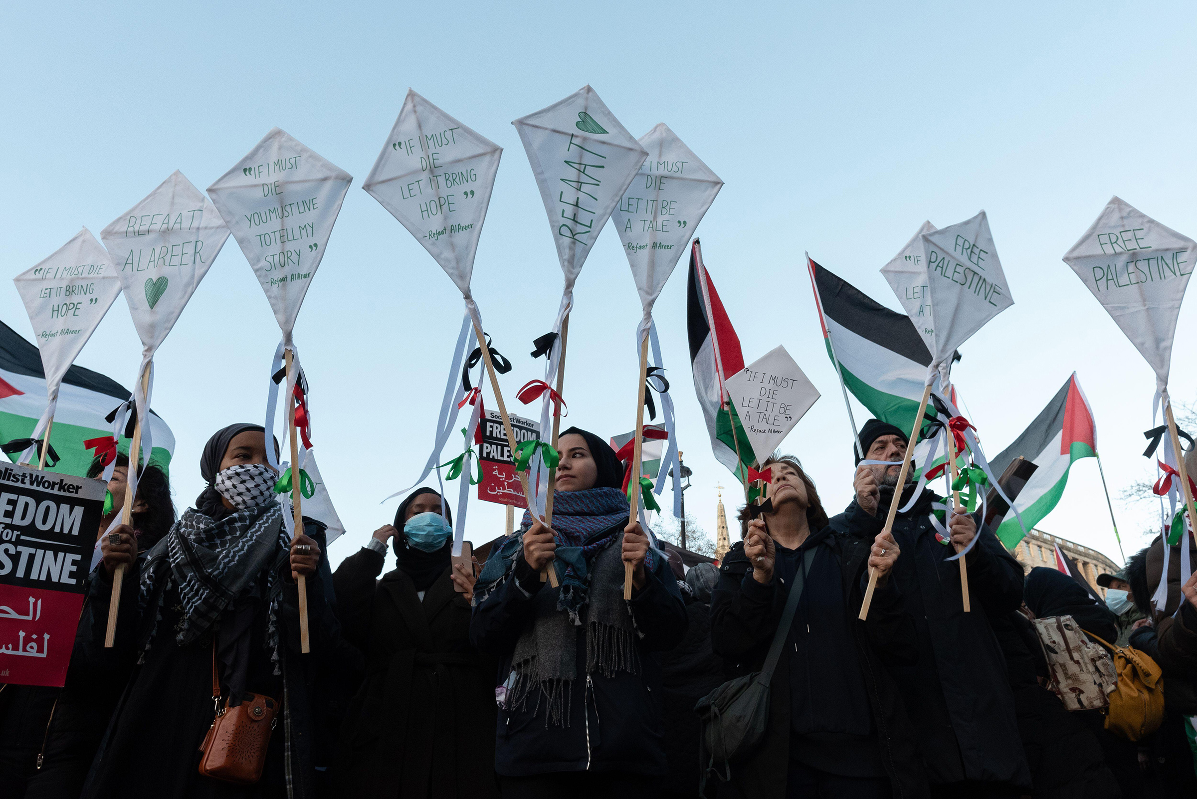 Protesters hold tributes to Palestinian writer, poet, and professor Refaat Alareer, who was killed by an Israeli airstrike, as tens of thousands of Palestine supporters march through central London to Whitehall calling for a permanent ceasefire and an end to UK and US support for Israel's siege, bombardment and invasion of Gaza, on Dec. 9.