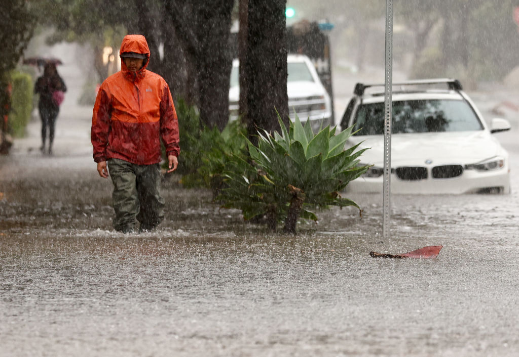 Isang tao na naglalakad sa isang bahaing kalye habang ang isang malakas na mahabang panahon ng atmospheric river storm, ang ikalawa sa loob ng mas mababa sa isang linggo, ay nakakaapekto sa California sa Peb. 4, 2024 sa Santa Barbara, California.  