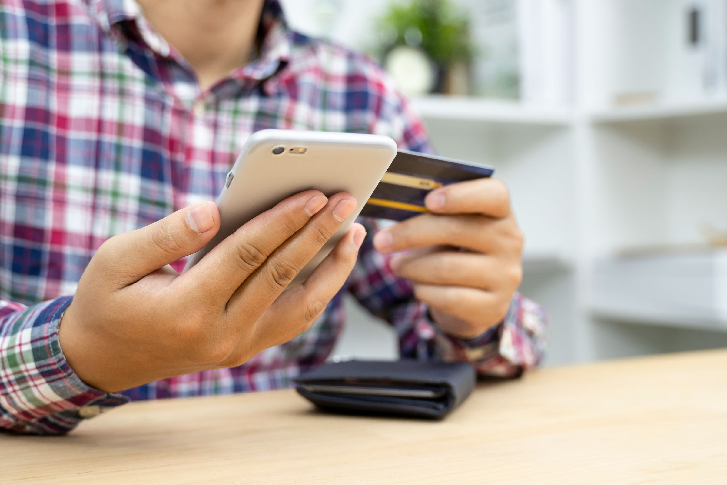 Young man hands holding credit card and using phone