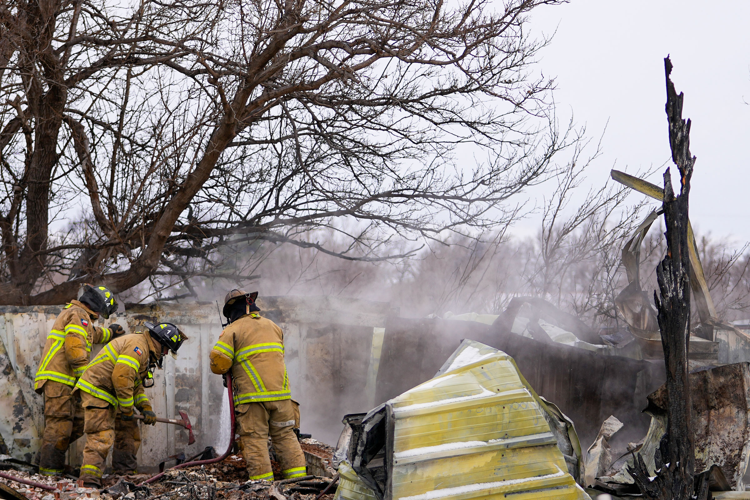 Mga opisyal ng sunog mula Lubbock, Texas, tumutulong sa pagpapatay ng mga nagliliyab na debris ng isang tahanan na nasira ng Smokehouse Creek Fire sa Stinnett, noong Peb. 29, 2024.