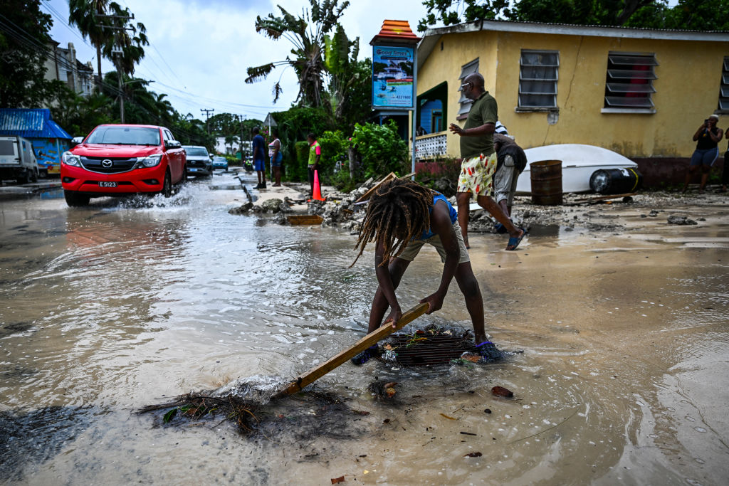 A boy clears rock from the street as it gets flooded after the hurricane Beryl in Barbados.