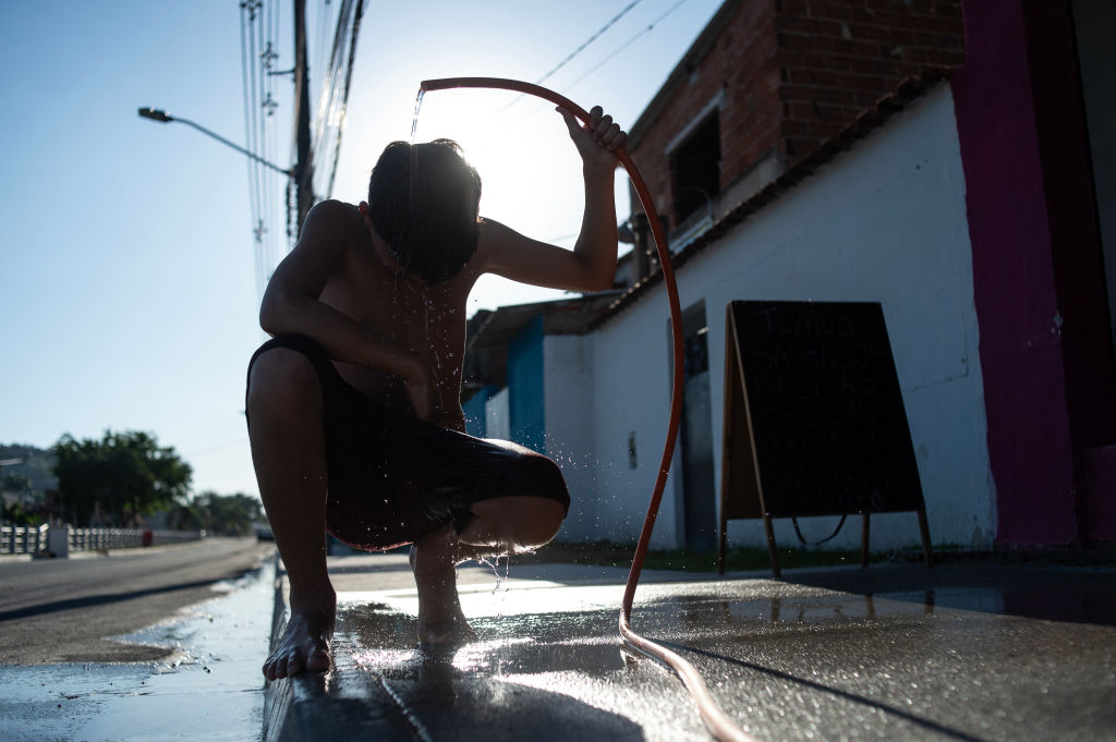 A boy cools off with a hose on the street amid a heat wave in the Guaratiba neighborhood of Rio de Janeiro, Brazil, on Feb. 17, 2025.