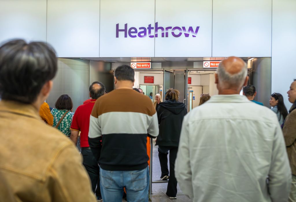 People wait to greet friends and relatives in front of a sign reading