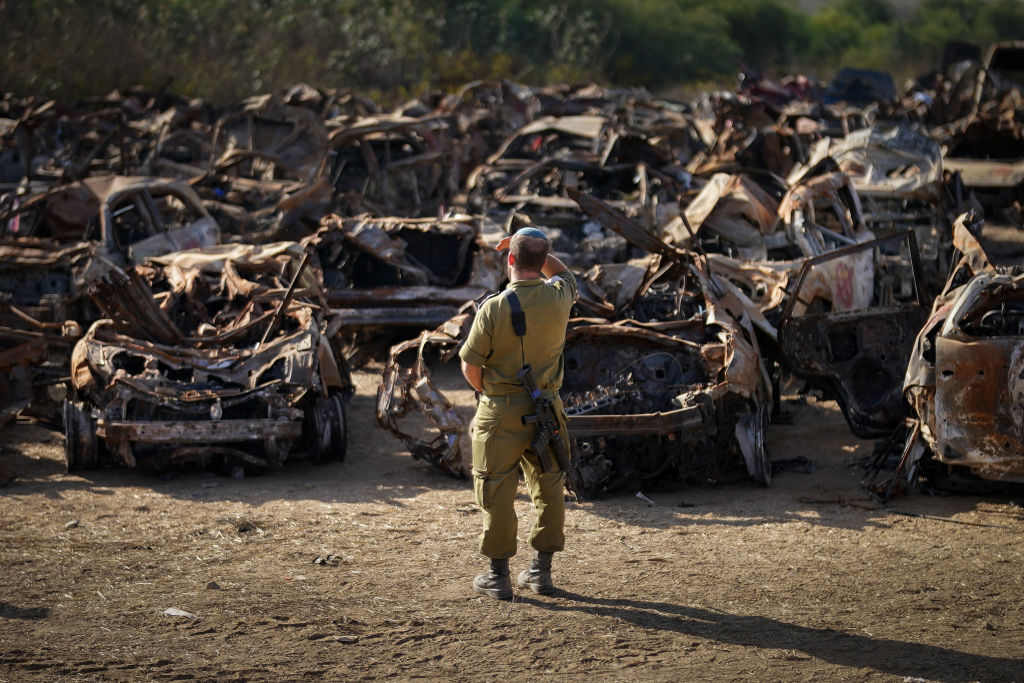Một binh sĩ Israel quan sát một kho chứa hàng trăm xe cộ bị phá hủy sau các cuộc tấn công của Hamas vào ngày 7 tháng 10 tại Tkuma, Israel, vào ngày 8 tháng 11 năm 2023.