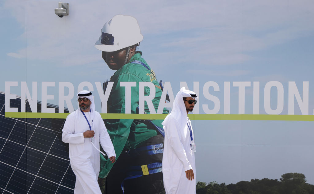 Lelaki memakai thawb berjalan melepasi papan iklan yang mempromosikan peralihan ke tenaga boleh diperbaharui di Persidangan COP28 Perubahan Iklim PBB di Dubai, Emiriah Arab Bersatu. 