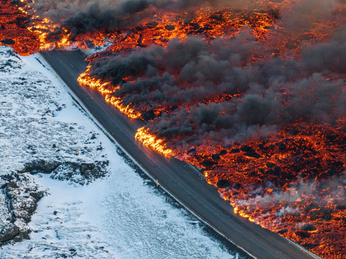 Pemandangan lava yang melintasi jalan utama ke Grindavík dan mengalir di jalan menuju Blue Lagoon, di Grindavík, Islandia.