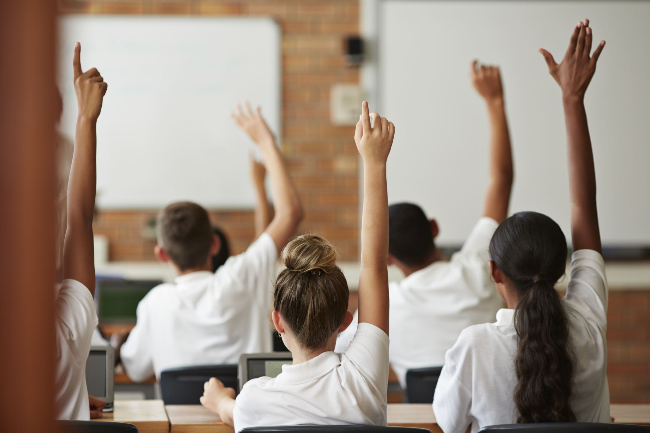 Schüler mit erhobenen Händen, Rückansicht