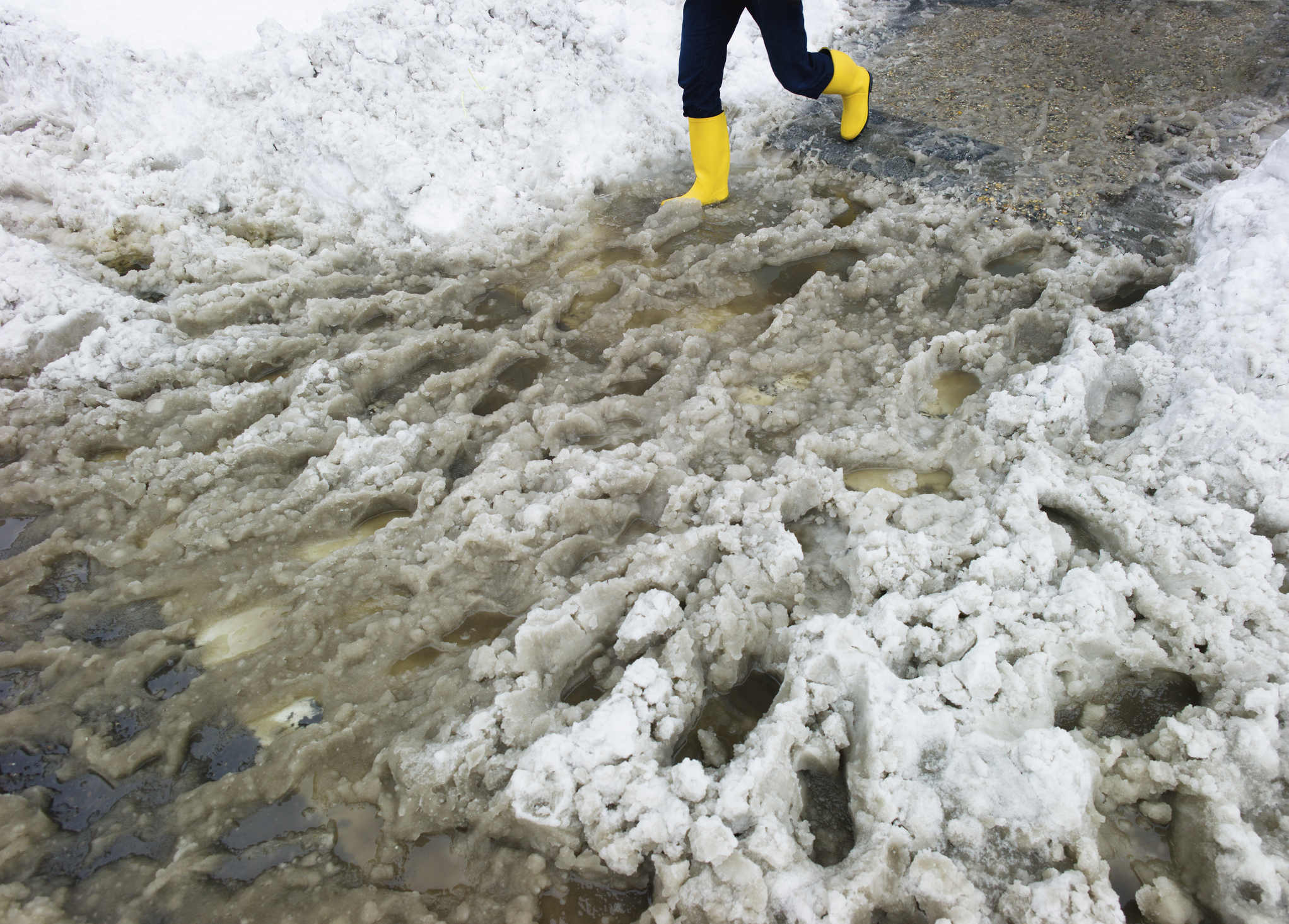 USA, New York, New York City, legs of person in yellow rubber boots walking in slush