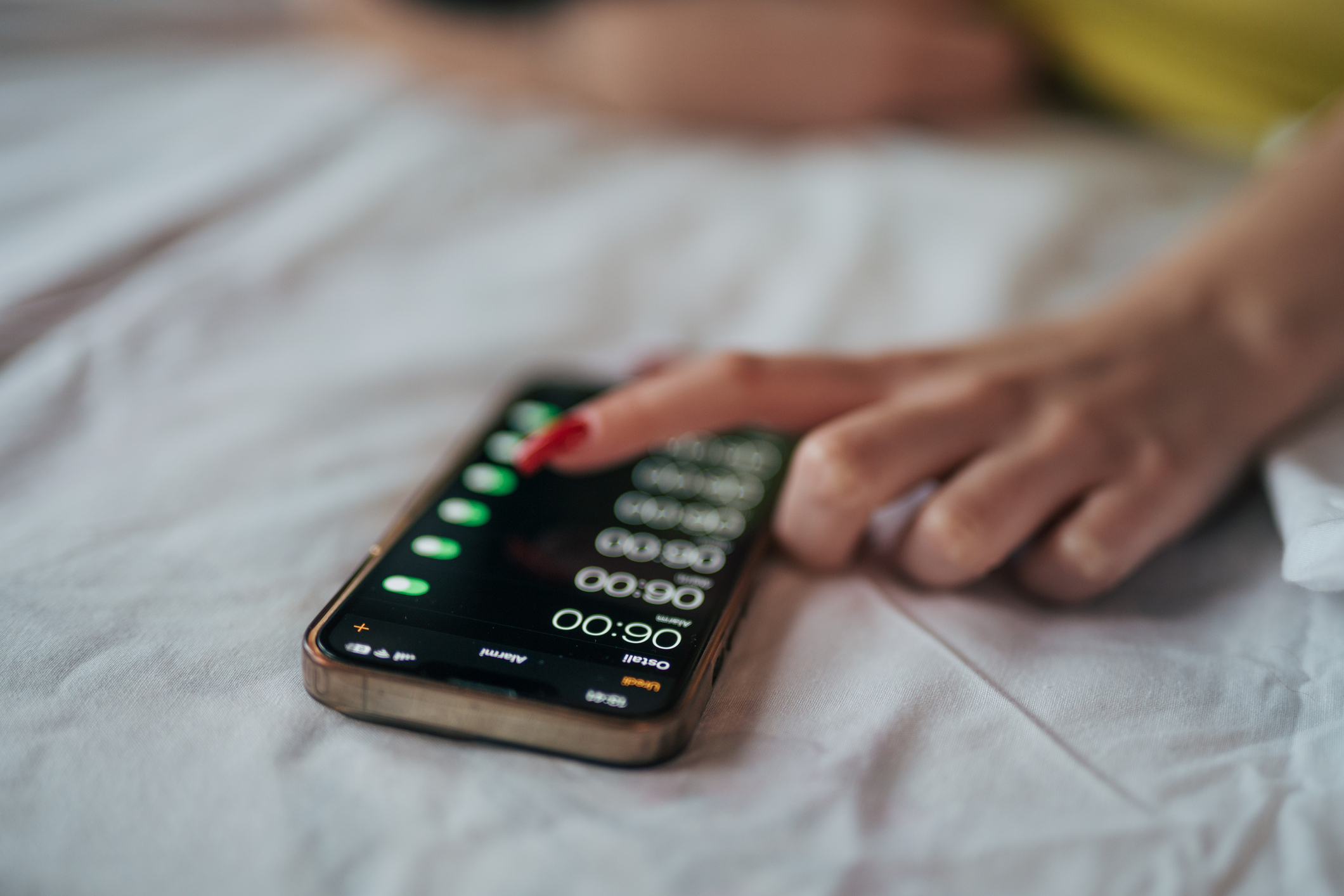 Eine junge Frau stellt einen Wecker auf ihrem Telefon ein