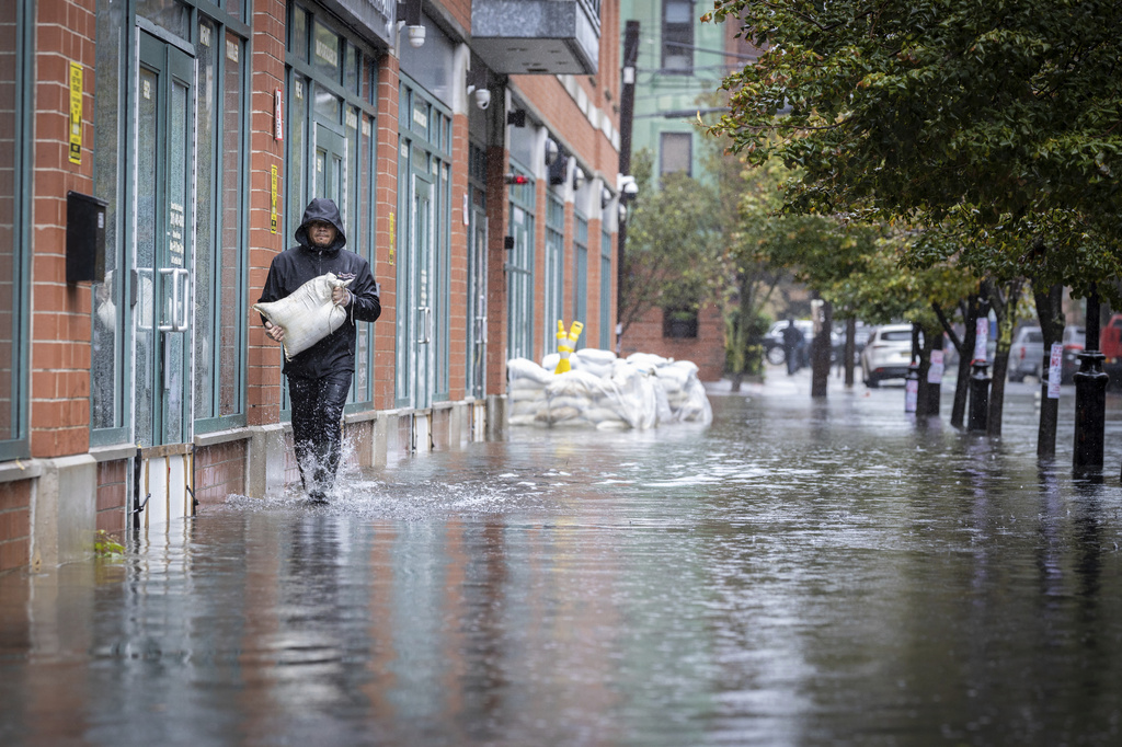 一個人在重雨引發街道水淹的情況下,於2023年9月29日在新澤西州霍博肯市運送沙包。根據一份龐大的新政府報告,已加劇的氣候變化現在滲透到美國人每日生活的各個層面,造成的影響「已經遍及全美各地,並在每個地區惡化。」