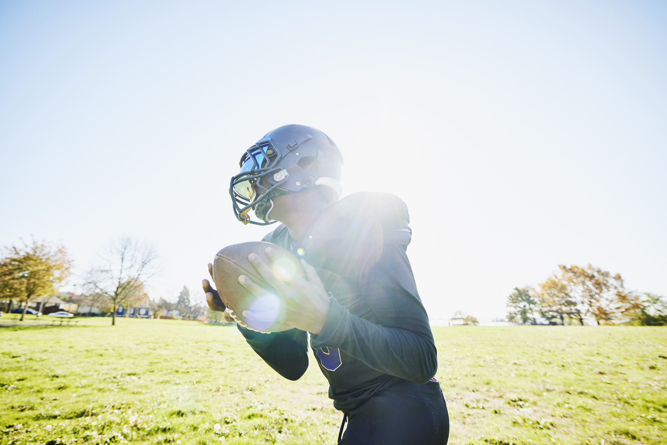 Medium shot of young football player catching pass during practice on fall afternoon