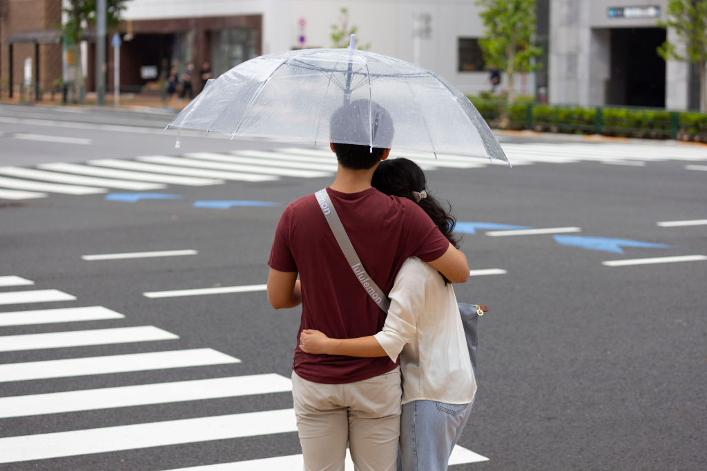 Couple hugs underneath an umbrella at a crossroad