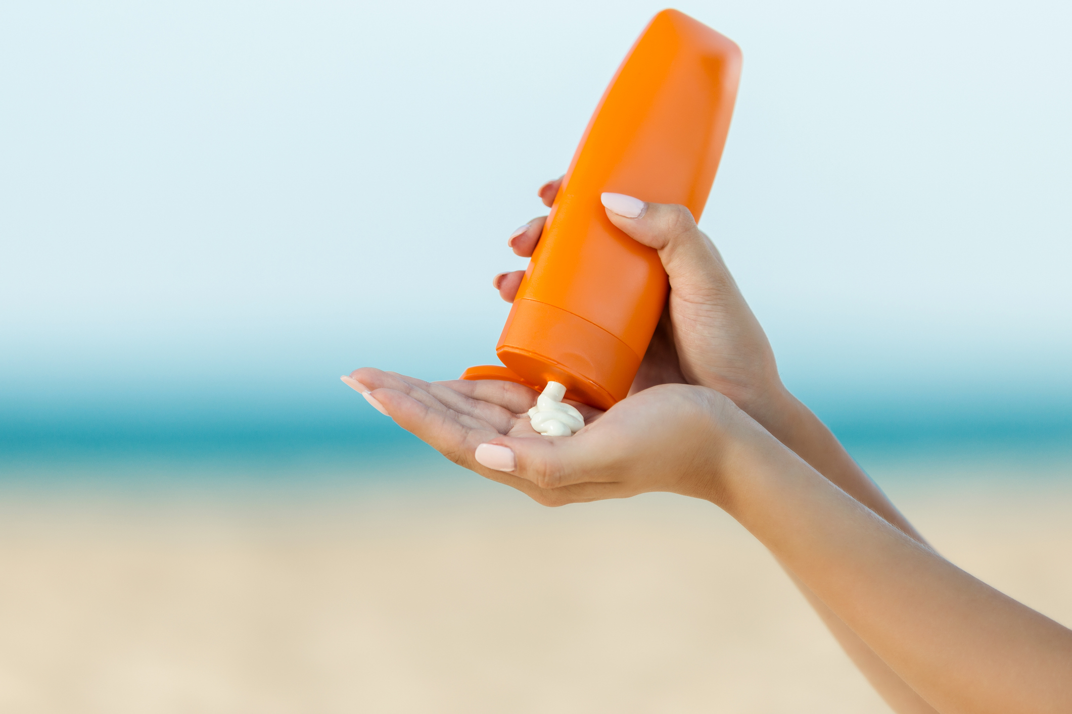 Woman hand apply sunscreen on the beach