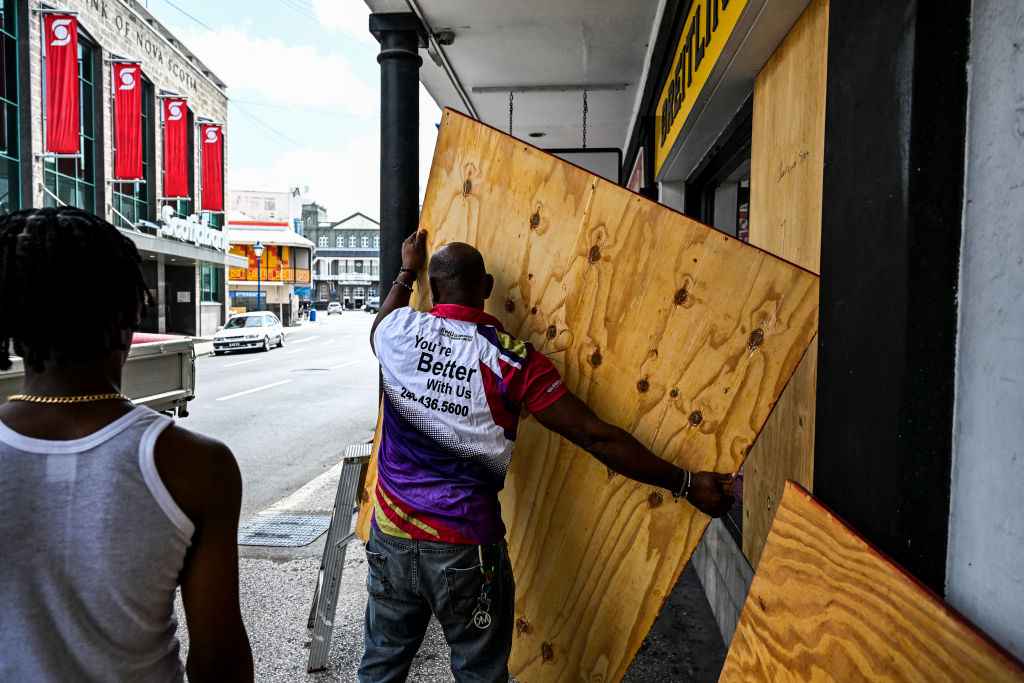 A man prepares to board up a shop window as people prepare for the arrival of Hurricane Beryl in Bridgetown, Barbados on June 30, 2024. 