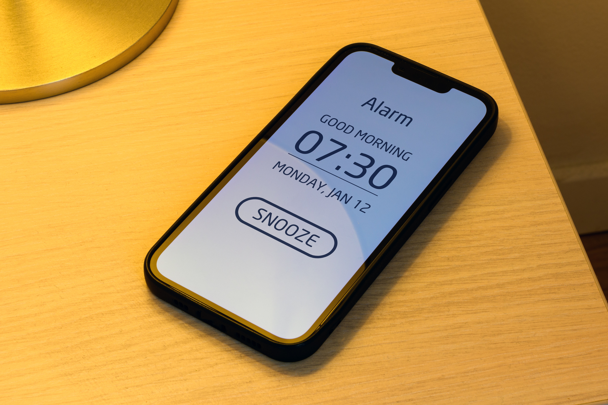 Smartphone alarm clock on bedroom night table with snooze button