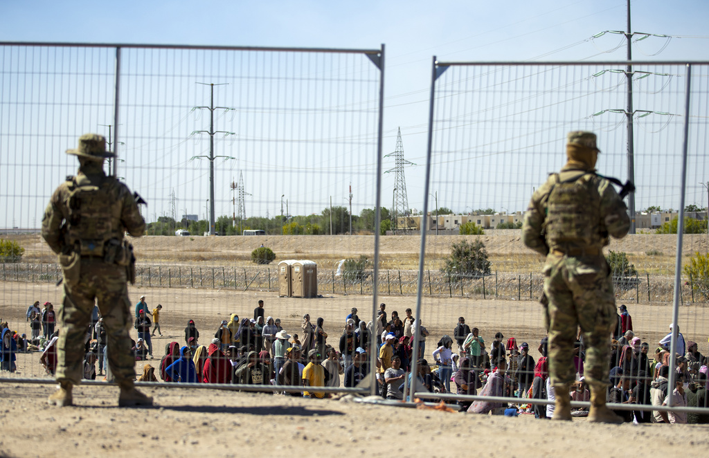 边境围栏旁排队等候进入德克萨斯州埃尔帕索的移民，得克萨斯州国民警卫队正在监视，2023 年 5 月 10 日。